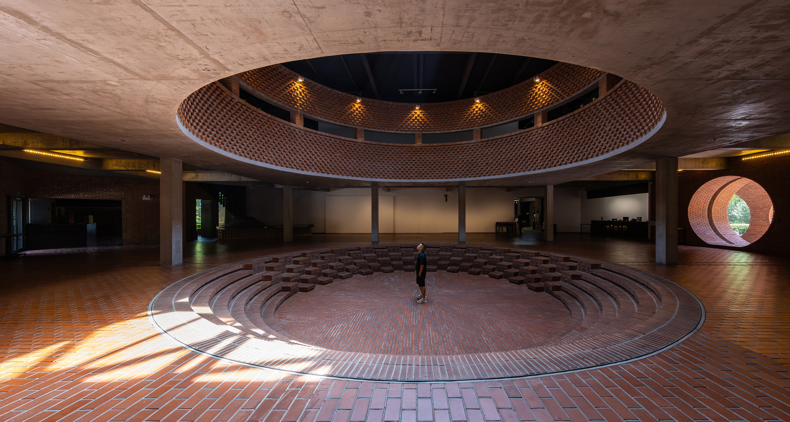 Circular brick auditorium beneath a wide concrete oculus.